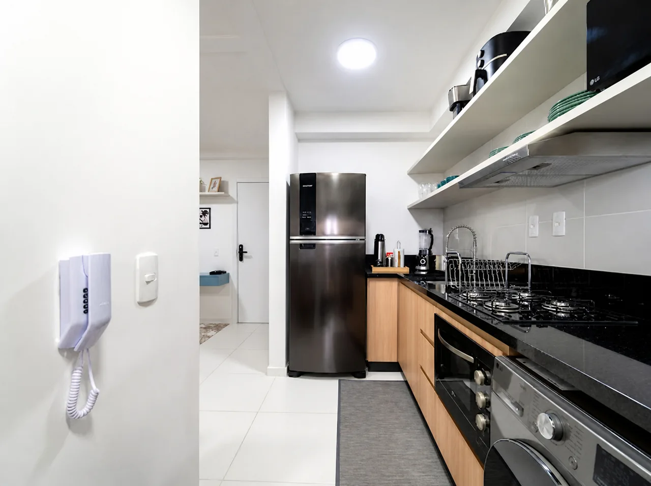 Cozinha equipada com geladeira, cooktop, forno, micro-ondas e máquina de lavar