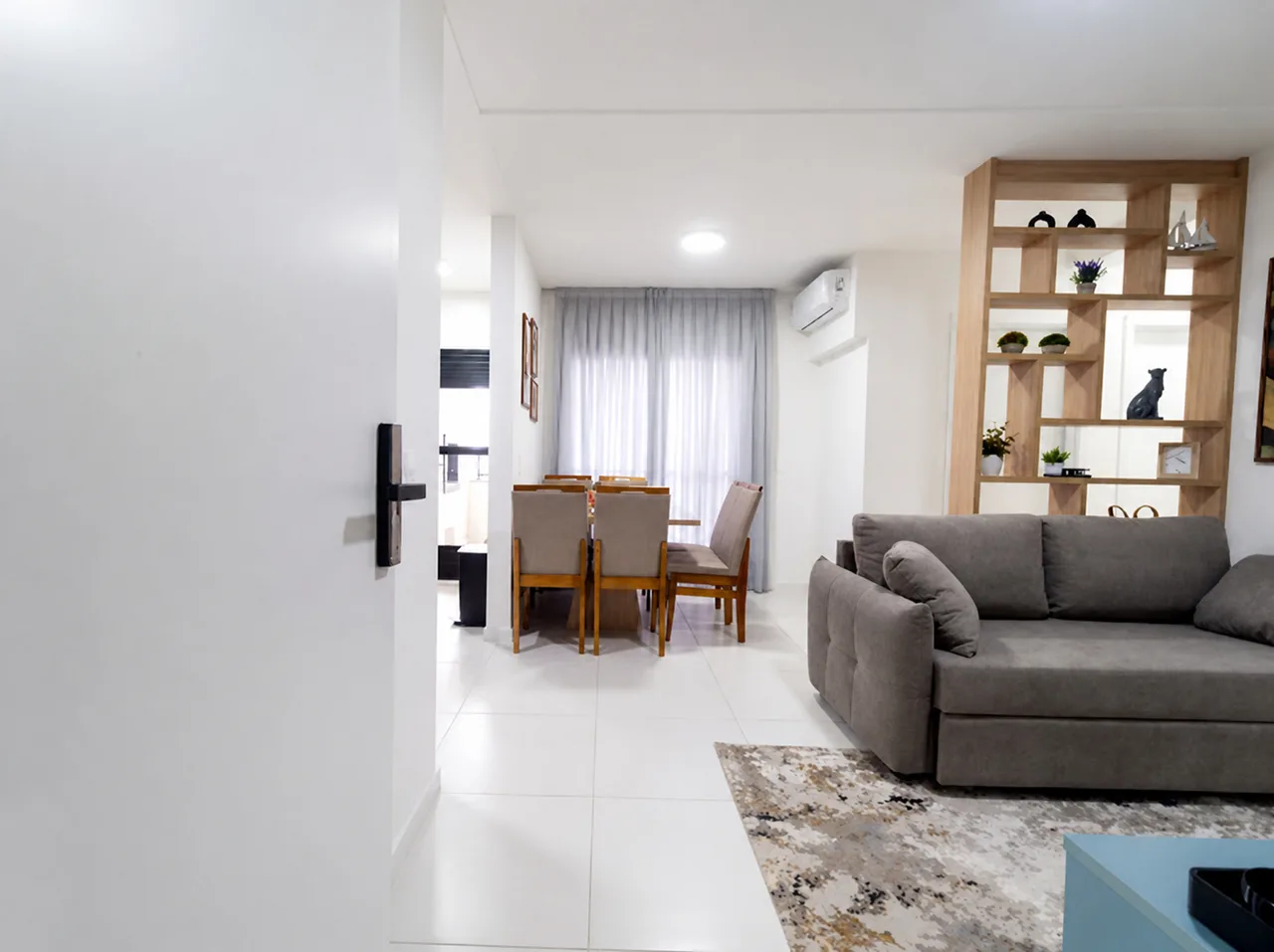 Corredor de entrada do apartamento levando à sala e à mesa de jantar