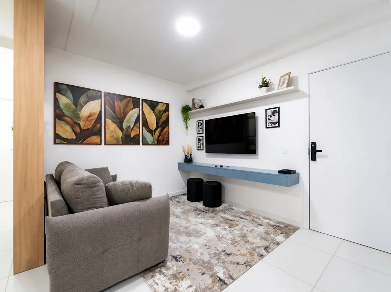 Sofá e Smart TV na parede da sala, com aparador azul suspenso