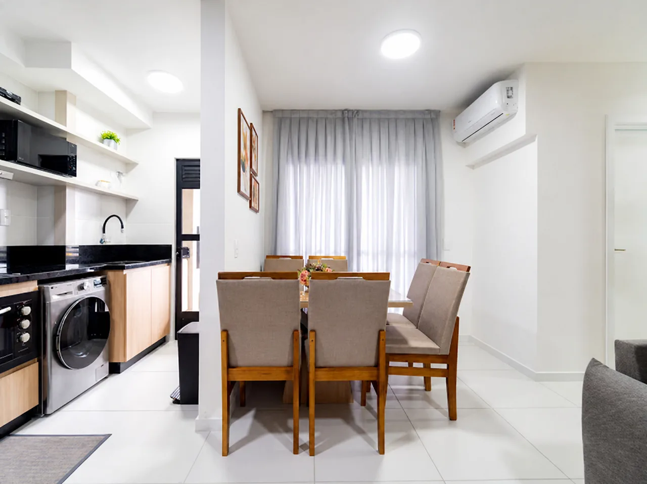 Sala de jantar integrada à cozinha e à área de serviço, com cortina clara