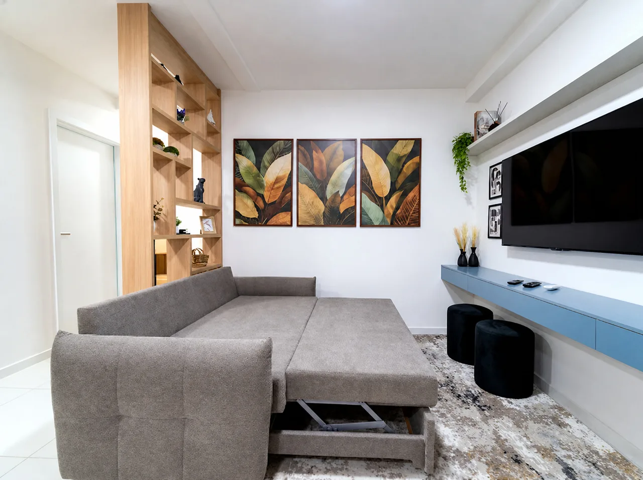 Sofá-cama aberto na sala, com a cama extra montada de frente para a TV